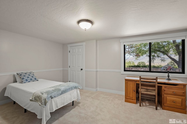 bedroom featuring light colored carpet and a textured ceiling