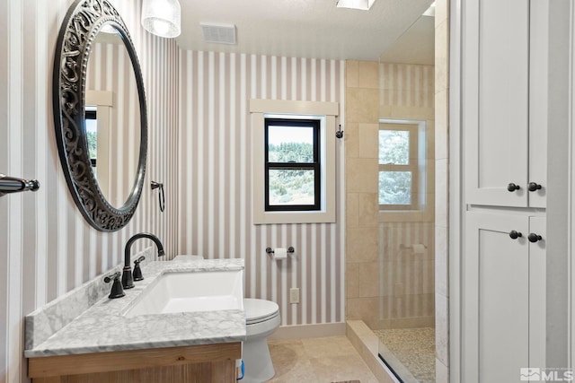 bathroom featuring tiled shower, tile patterned flooring, vanity, and toilet