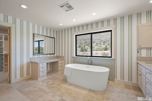 bathroom featuring a wealth of natural light, vanity, and a bath