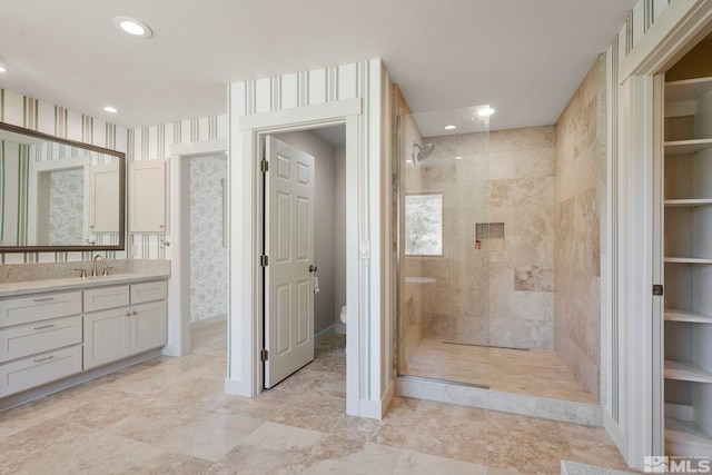bathroom with tiled shower, vanity, and toilet