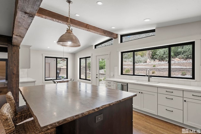 kitchen with backsplash, sink, hanging light fixtures, light hardwood / wood-style flooring, and white cabinetry