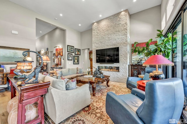 living room with a fireplace, a towering ceiling, and light hardwood / wood-style flooring