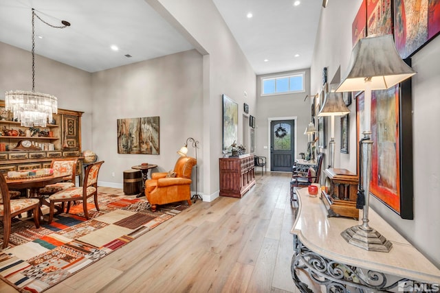 entryway with a high ceiling, light hardwood / wood-style flooring, and a notable chandelier