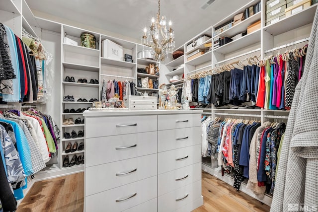 walk in closet with a chandelier and light hardwood / wood-style flooring