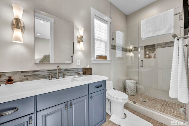 bathroom featuring decorative backsplash, toilet, an enclosed shower, and vanity