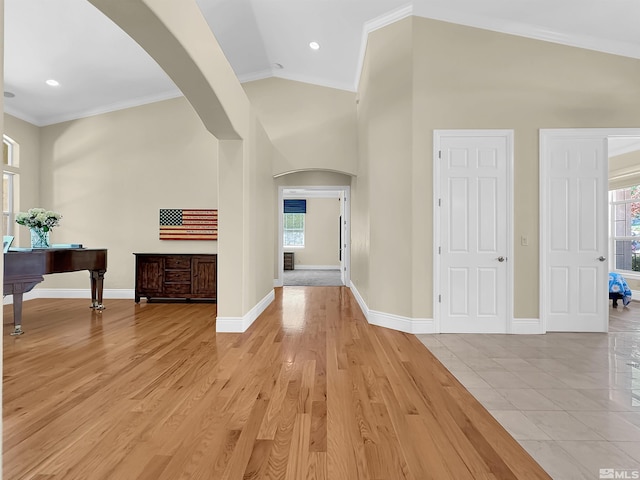 foyer featuring light hardwood / wood-style flooring, ornamental molding, plenty of natural light, and lofted ceiling