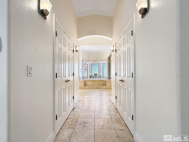 hallway with light tile patterned floors and crown molding