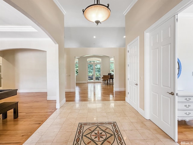 foyer with french doors, crown molding, and light tile patterned flooring