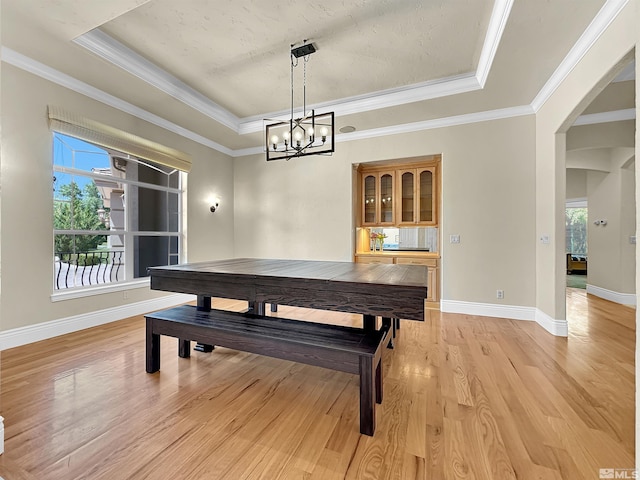 dining room featuring crown molding, an inviting chandelier, light hardwood / wood-style flooring, and a raised ceiling