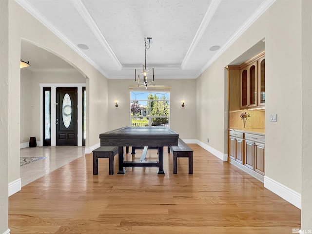 dining area featuring ornamental molding, light hardwood / wood-style flooring, and a tray ceiling