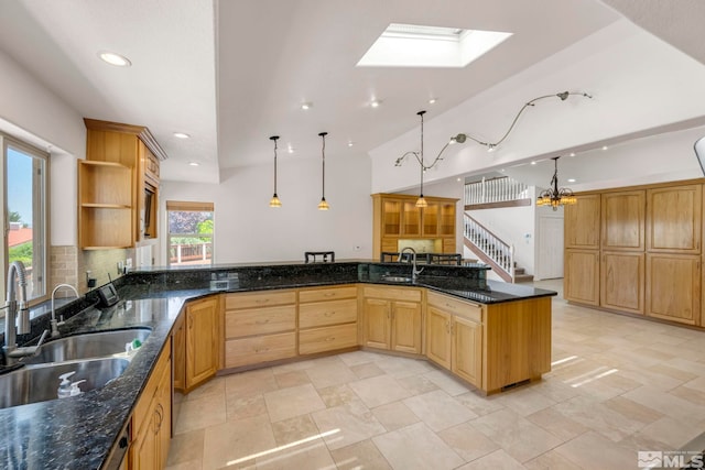 kitchen with dark stone counters, sink, hanging light fixtures, and light brown cabinets