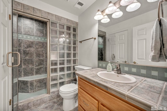 bathroom with tile patterned floors, vanity, toilet, and walk in shower