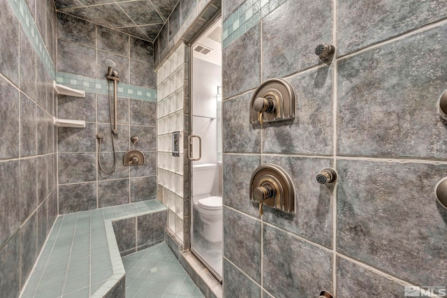 bathroom featuring a tile shower and toilet