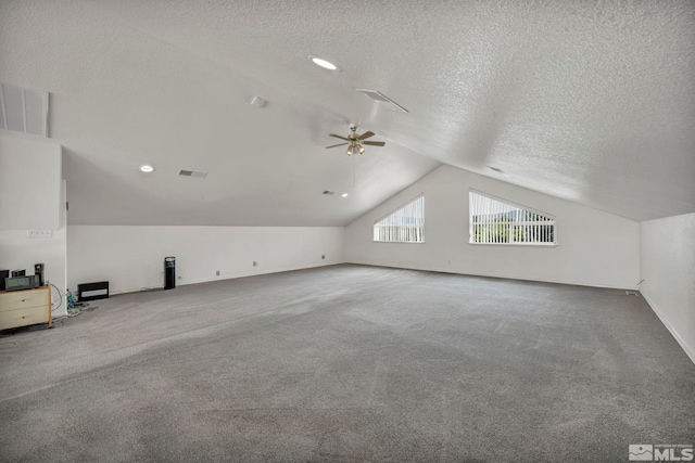 additional living space with carpet flooring, a textured ceiling, vaulted ceiling, and ceiling fan