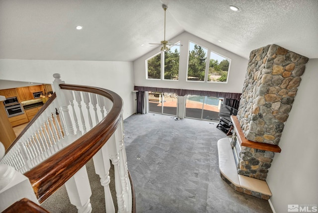 interior space with carpet flooring, ceiling fan, a textured ceiling, and vaulted ceiling