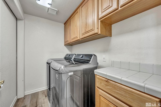 washroom with cabinets, separate washer and dryer, and light hardwood / wood-style flooring