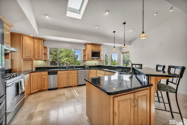 kitchen featuring sink, a breakfast bar area, a skylight, decorative light fixtures, and stainless steel appliances