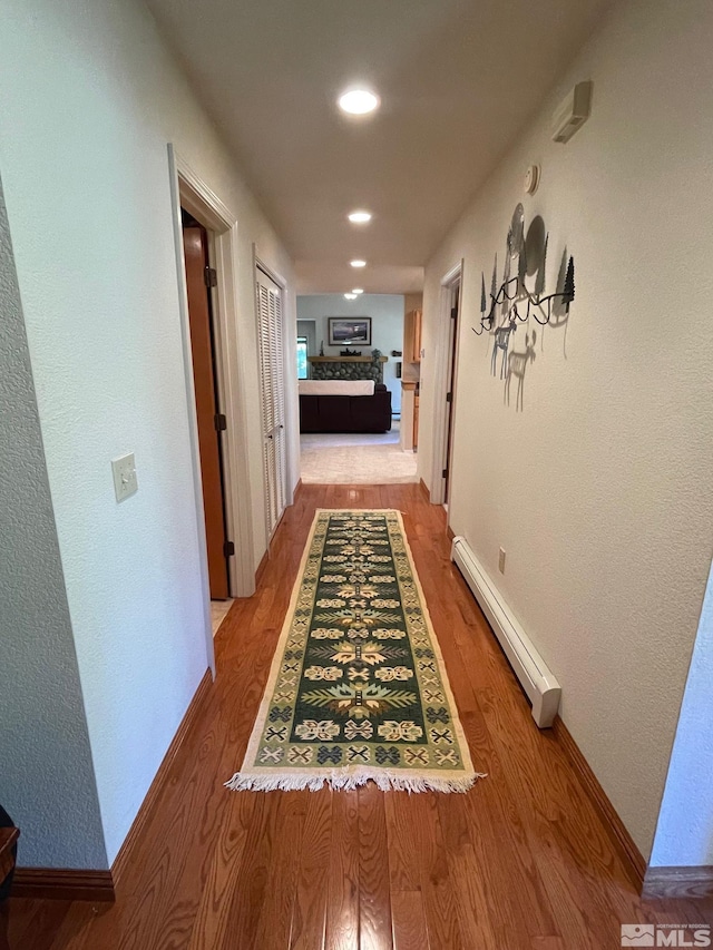 hall with hardwood / wood-style floors and a baseboard radiator