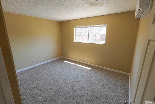 spare room featuring a wall mounted air conditioner, carpet floors, and a textured ceiling