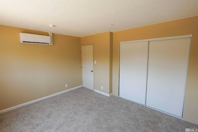 unfurnished bedroom with an AC wall unit, a closet, carpet floors, and a textured ceiling