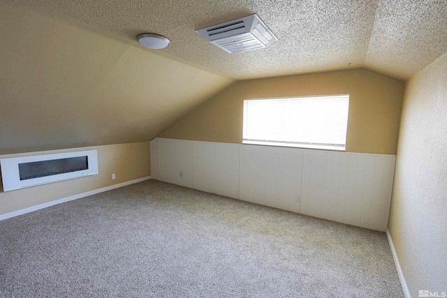 bonus room featuring light colored carpet, lofted ceiling, and a textured ceiling