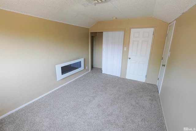 unfurnished bedroom featuring carpet flooring, a textured ceiling, a closet, and lofted ceiling