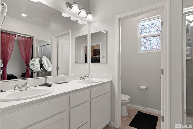 bathroom featuring toilet, vanity, tile patterned flooring, and a shower with door