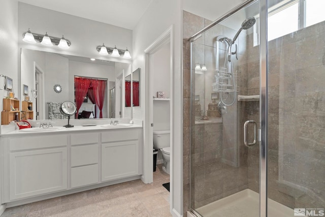 bathroom with toilet, vanity, and a shower with shower door