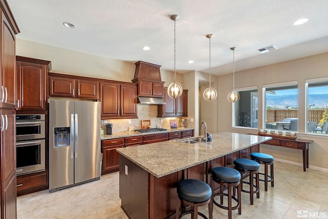 kitchen with light tile patterned flooring, backsplash, appliances with stainless steel finishes, pendant lighting, and sink