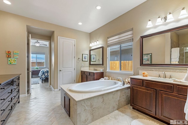 bathroom with tile patterned flooring, tiled tub, double vanity, and ceiling fan