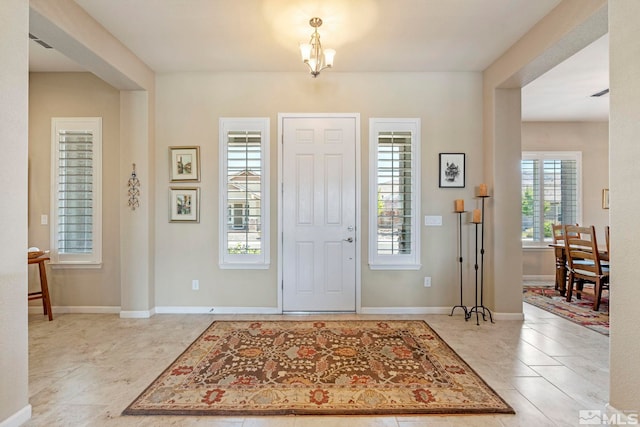 tiled foyer entrance with a chandelier