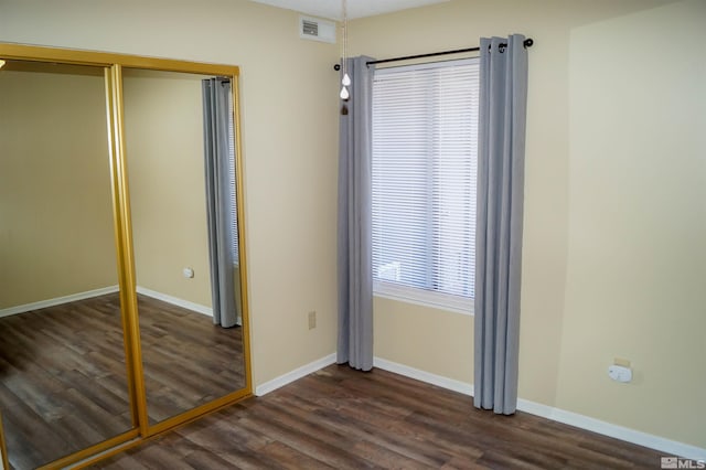 unfurnished bedroom with dark hardwood / wood-style flooring and a closet