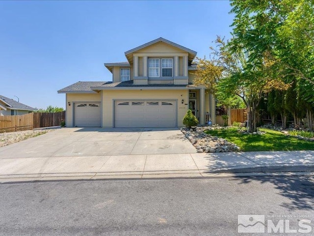 traditional-style home featuring a garage, concrete driveway, and fence