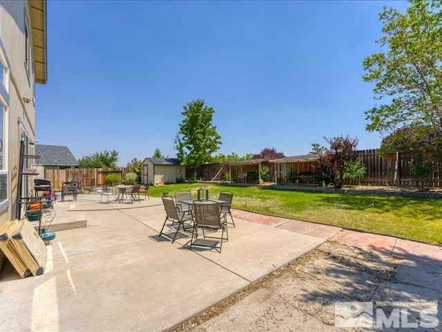 view of patio with a storage shed, outdoor dining space, an outbuilding, and a fenced backyard