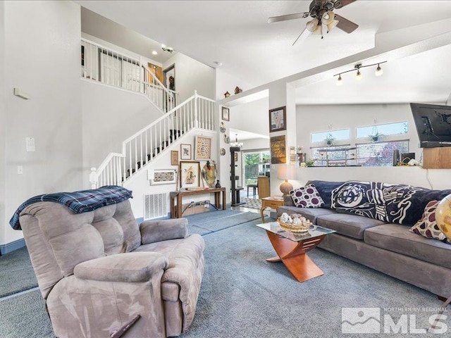 carpeted living room with high vaulted ceiling, stairway, and ceiling fan with notable chandelier