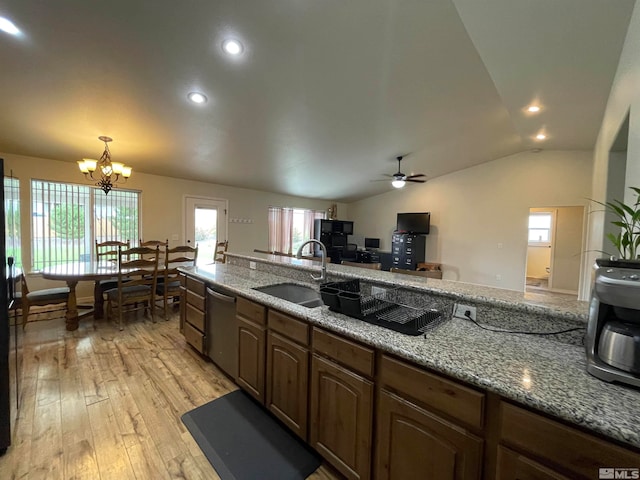 kitchen featuring ceiling fan with notable chandelier, light stone counters, light hardwood / wood-style floors, vaulted ceiling, and sink