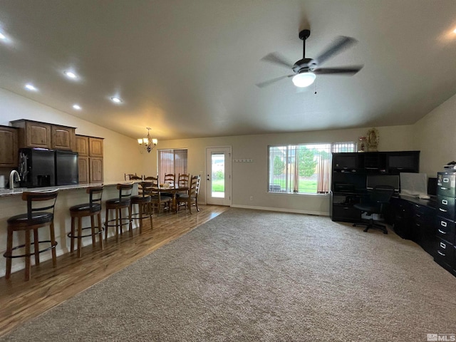 carpeted living room with sink, ceiling fan with notable chandelier, and vaulted ceiling