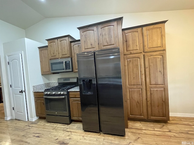 kitchen with black refrigerator with ice dispenser, vaulted ceiling, gas range, and light wood-type flooring