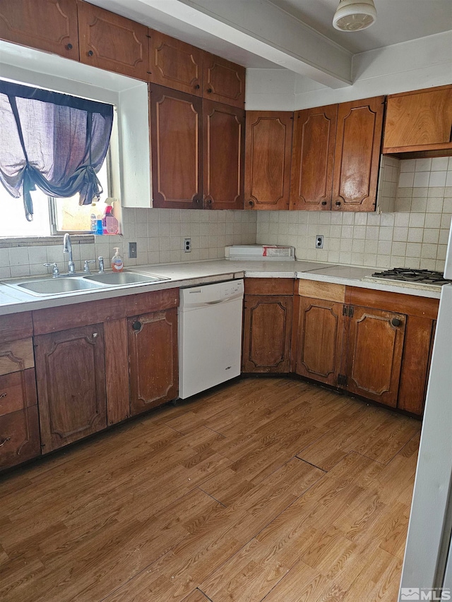 kitchen with backsplash, sink, light wood-type flooring, and white dishwasher