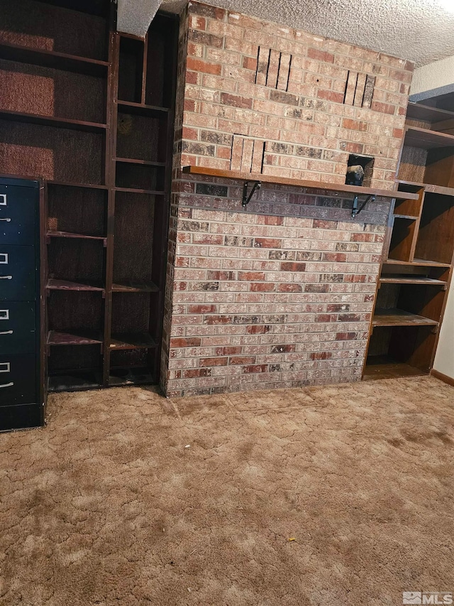 unfurnished living room with brick wall, carpet, and a textured ceiling