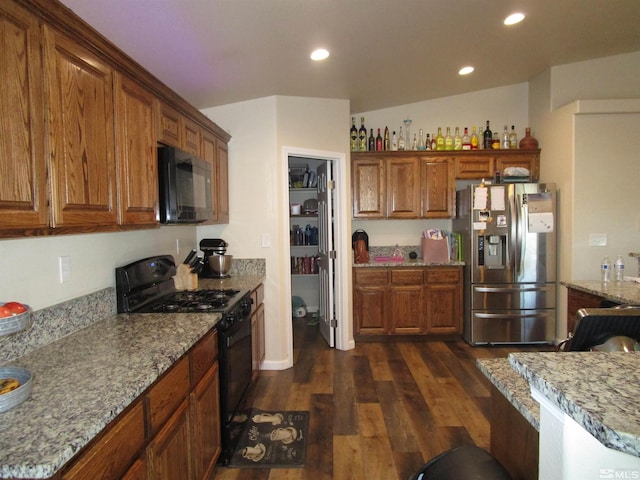 kitchen featuring light stone countertops, black appliances, dark hardwood / wood-style flooring, and vaulted ceiling