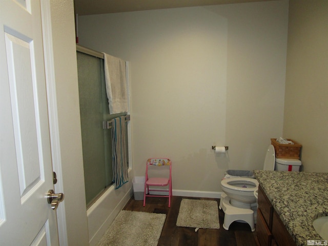 full bathroom with wood-type flooring, toilet, vanity, and shower / bath combination with glass door