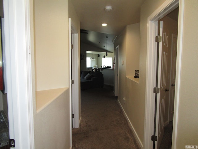 hall with vaulted ceiling and dark carpet