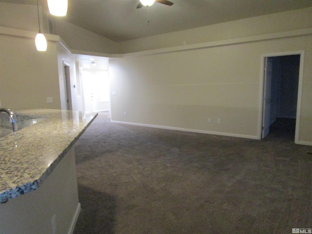 unfurnished living room featuring vaulted ceiling, dark colored carpet, and ceiling fan