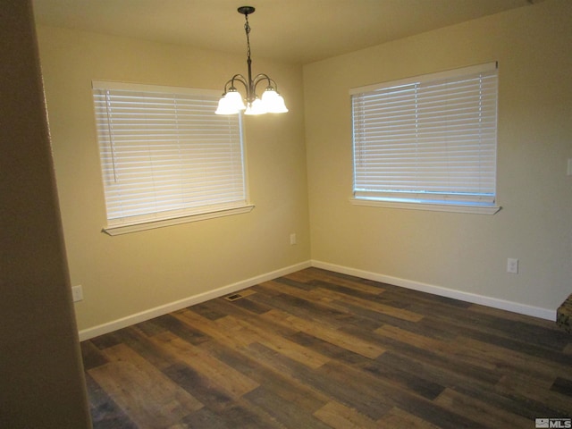 empty room with dark hardwood / wood-style flooring and a notable chandelier