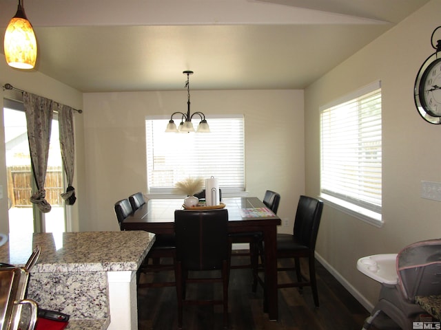 dining space with dark hardwood / wood-style floors and a notable chandelier