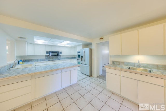 kitchen featuring tile countertops, sink, white cabinetry, and black appliances