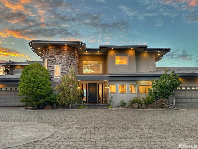 exterior space with stone siding, decorative driveway, and stucco siding