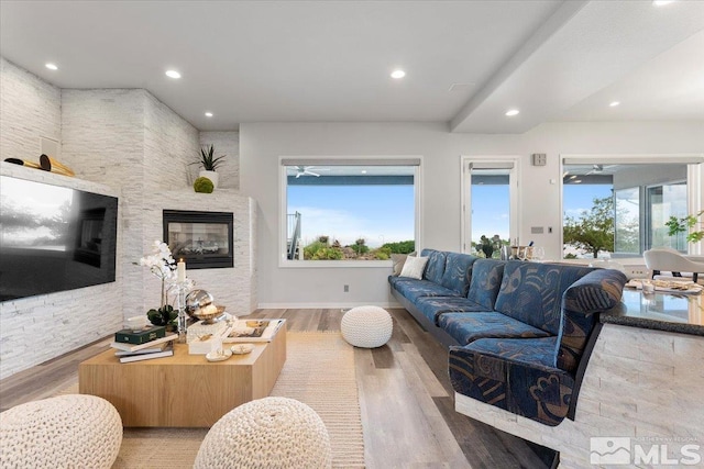 living area with a wealth of natural light, a glass covered fireplace, recessed lighting, and wood finished floors