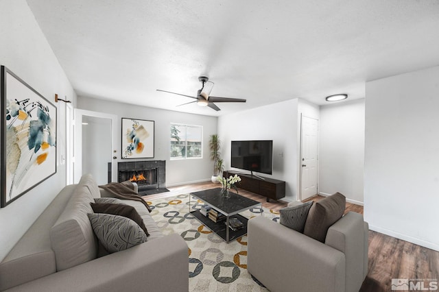 living room with a tile fireplace, ceiling fan, and hardwood / wood-style floors